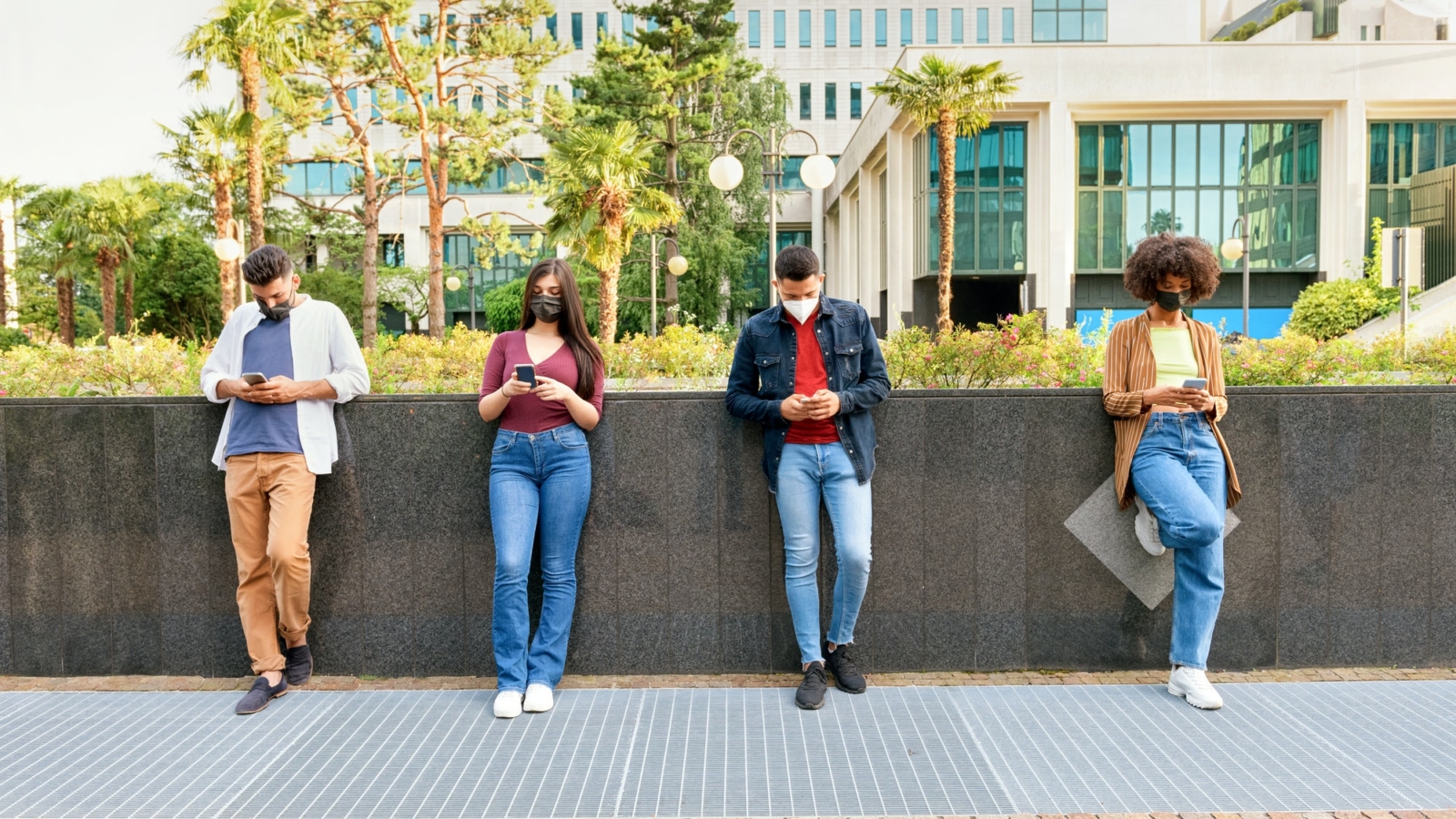 Four young friends wearing masks and social distancing